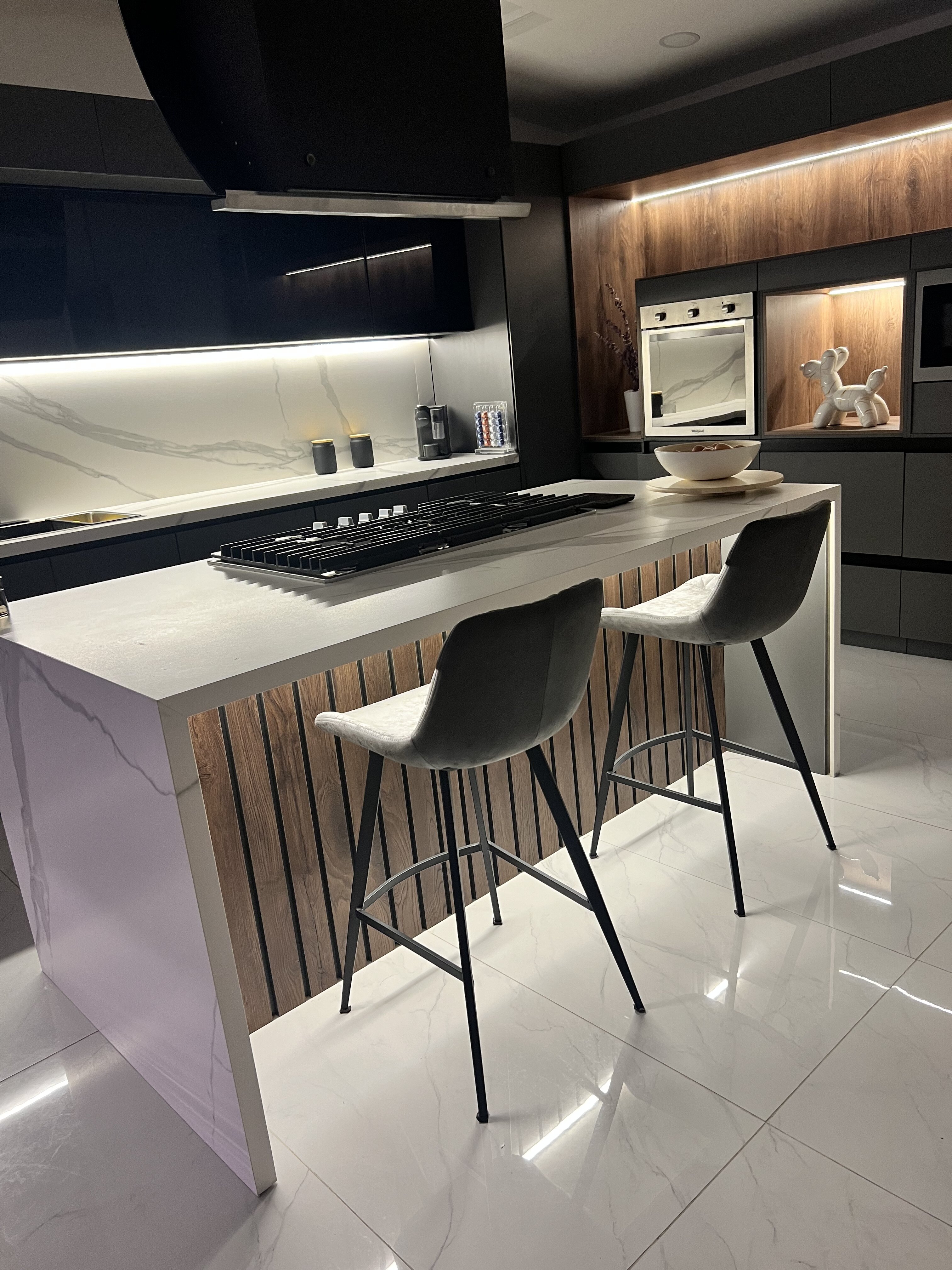 Cocina terminada con isla de mármol, paneles de madera y bancos grises